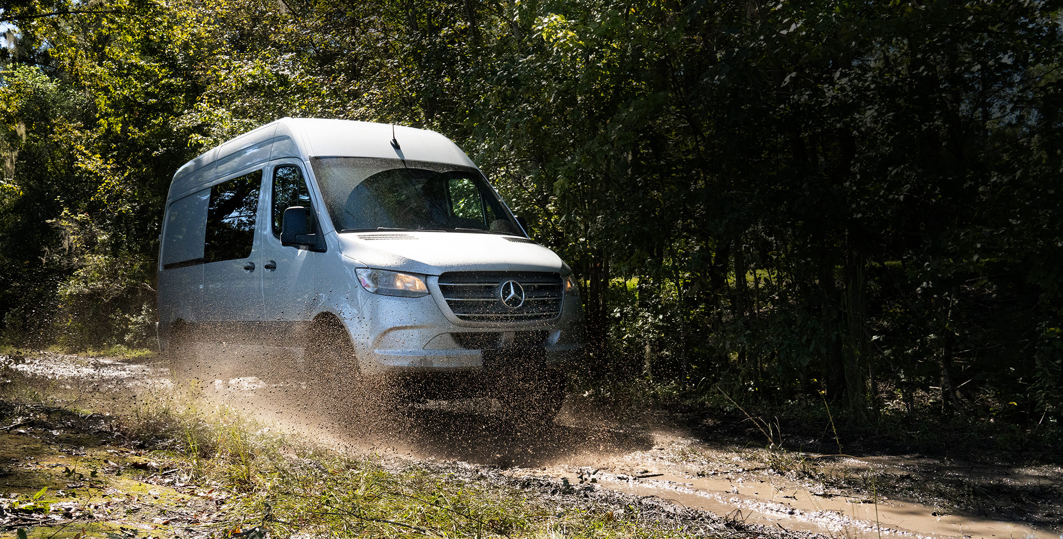 A Mercedes-Benz Sprinter has been converted to go glamping, her is an action shot driving through the woods!