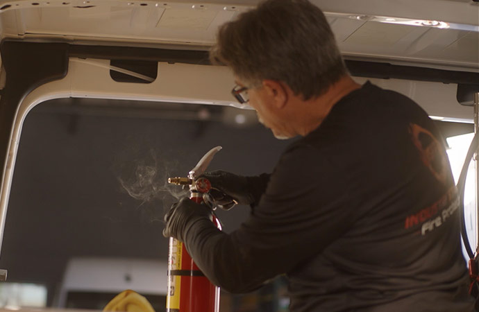 Clickable video still of man filling fire extinguisher in Sprinter van.