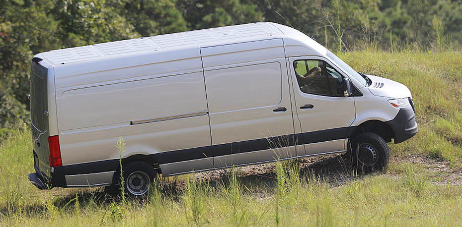 View of Sprinter  van traveling up a slope, across a field.